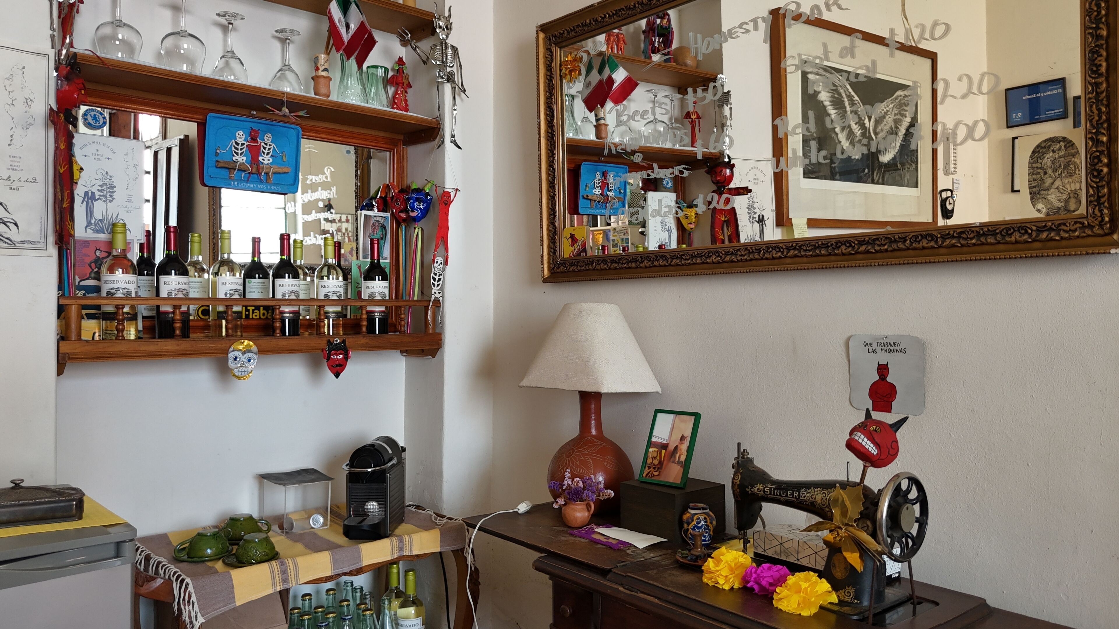 Una habitación con una barra de madera que exhibe varias botellas, una máquina de coser y una lámpara.