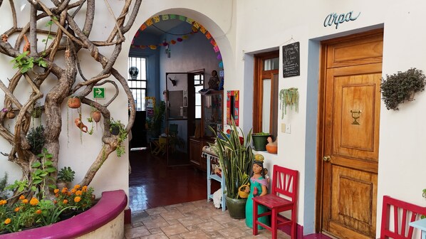 Una entrada acogedora con un árbol decorativo, una silla roja y una puerta de madera.