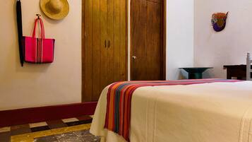 Una habitación de hotel con una cama, un armario, un sombrero y un bolso en la pared.