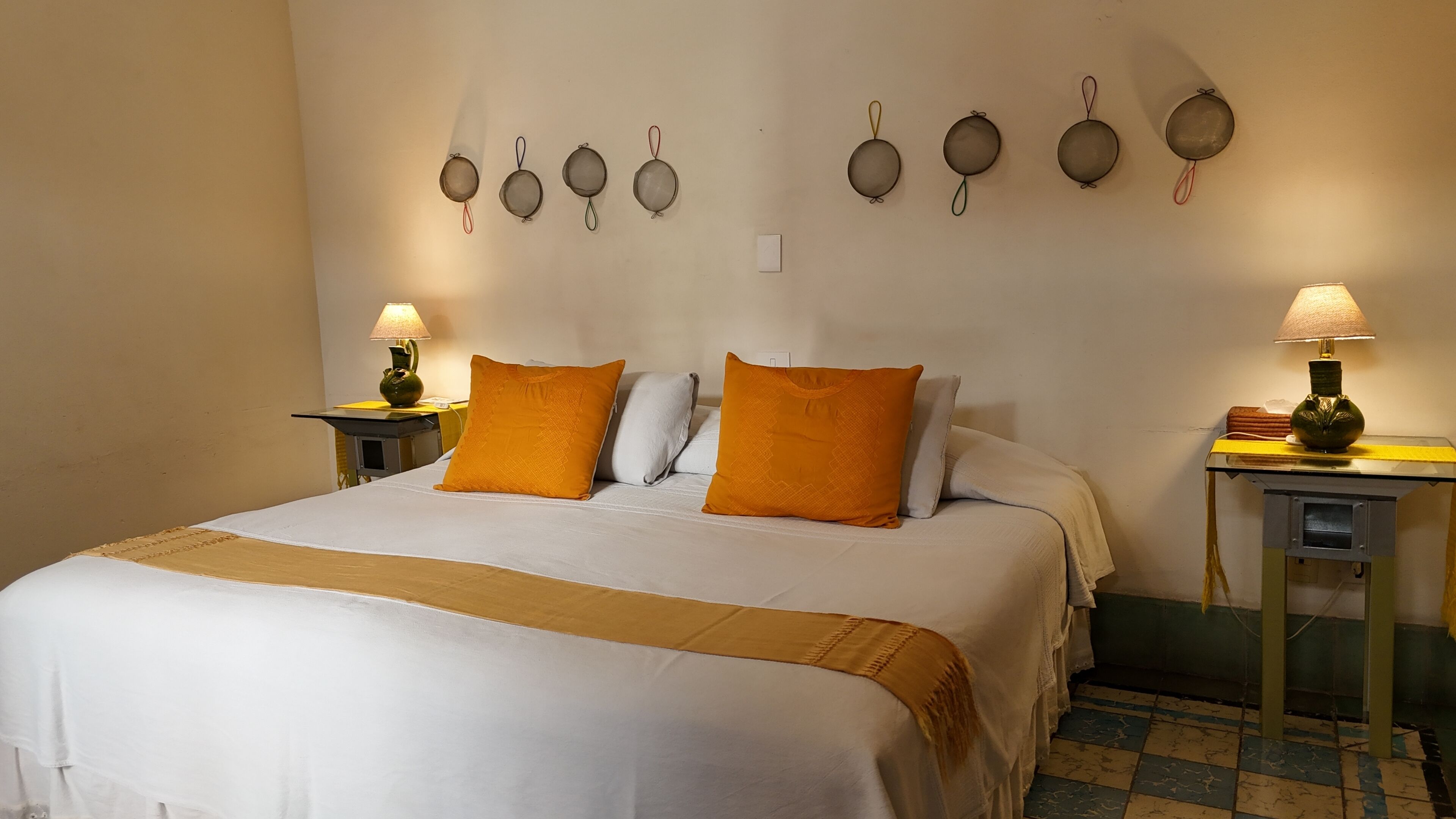 A hotel room with a large bed, two nightstands, a wall-mounted lamp, and a checkered floor.