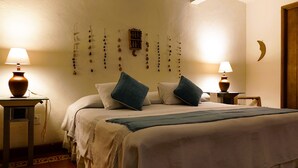 A neatly made bed with two pillows, a bedside table with a lamp, and wall decorations including a crescent moon and hanging ornaments. - El Diablo y la Sandia B&B (Oaxaca)