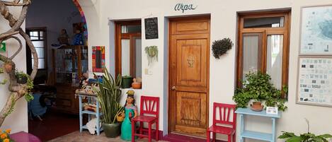 Una tienda pintoresca con puerta de madera, sillas rojas y macetas.