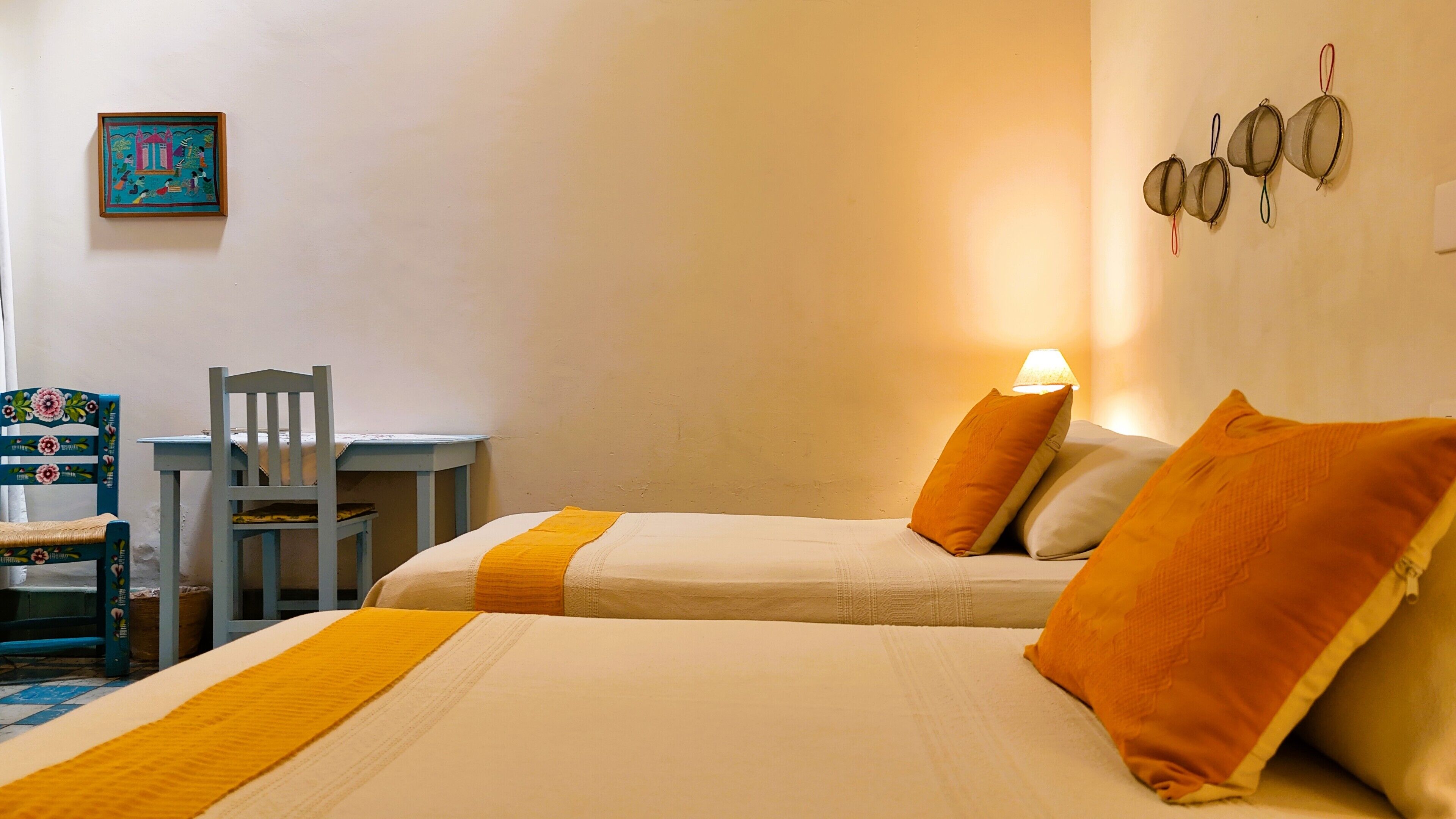 Una camera da letto con due letti, una scrivania, una sedia e una lampada a parete.
