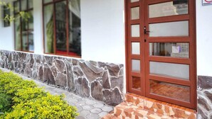 A building with a stone facade, a wooden door with glass panels, and a tiled entrance. - Suite San Vicente 1 Bathrooms Ecuador - Private Jacuzzi & Parking (Tungurahua)