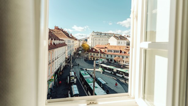 A view from a window of a street with buildings and buses. - Lilians Cosy Apartment Jakomini 3B (Graz)