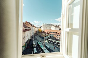 A view from a window of a street with buildings and buses.