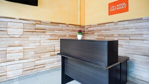 Una zona de recepción con pared de piedra, un mostrador de recepción de madera oscura y un letrero que dice 'Kool Kost' en la pared.
