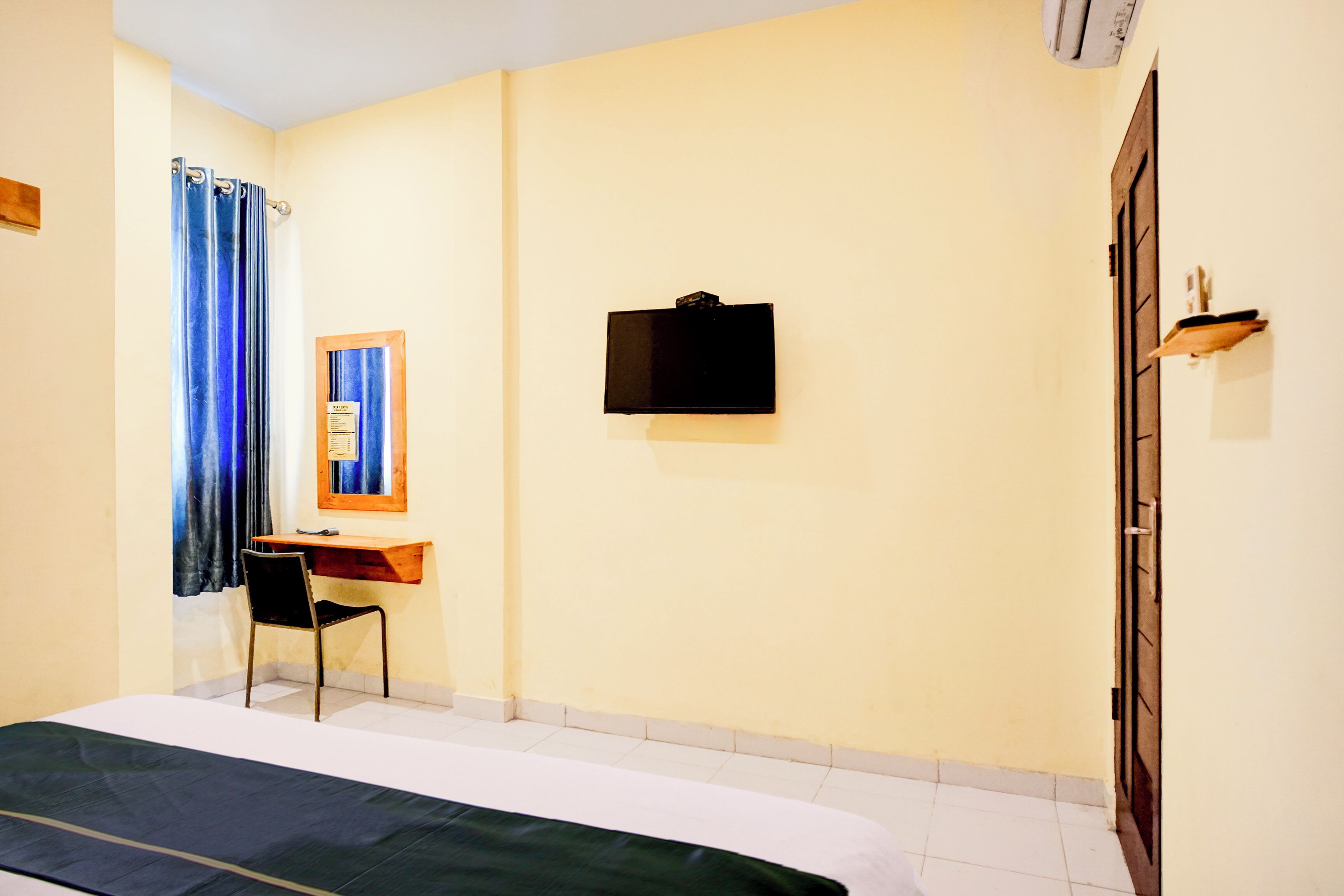 A room with a bed, a desk, a chair, a television, and a wardrobe.