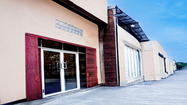 Un edificio con fachada moderna, puertas de vidrio grandes y un toldo rojo.