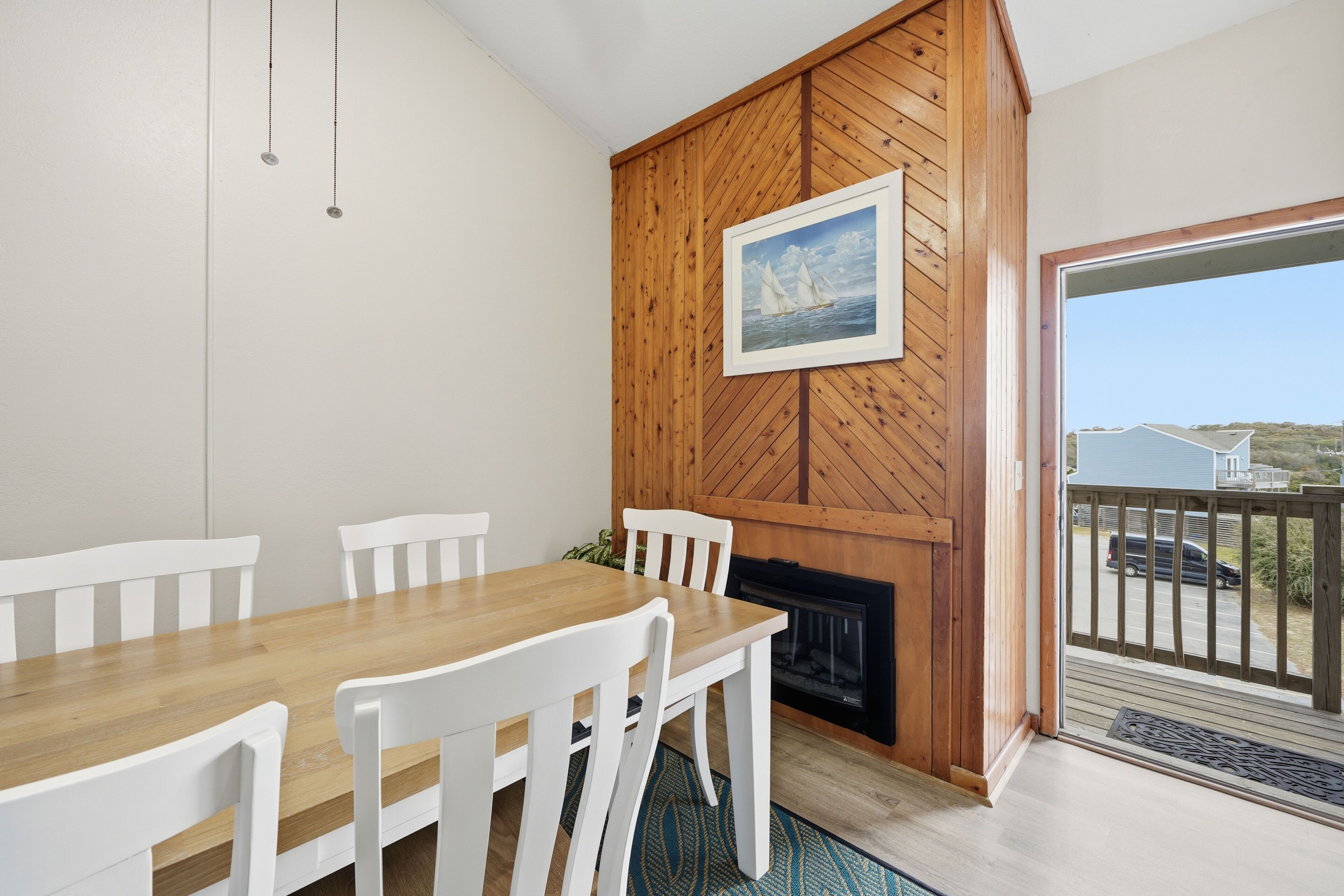 A dining area with a wooden table and white chairs, a fireplace, and a view of the outside.