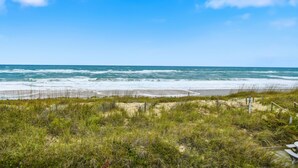 A beach with a wooden fence, grassy dunes, and the ocean. - Charming Coastal-Facing 2-Bedroom Condo in Duck (Duck)