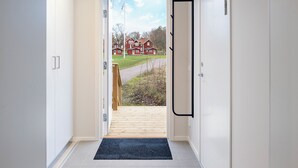 A hallway leading to a wooden deck with a view of a red house. - Skerike Golfhus (Vasteras)