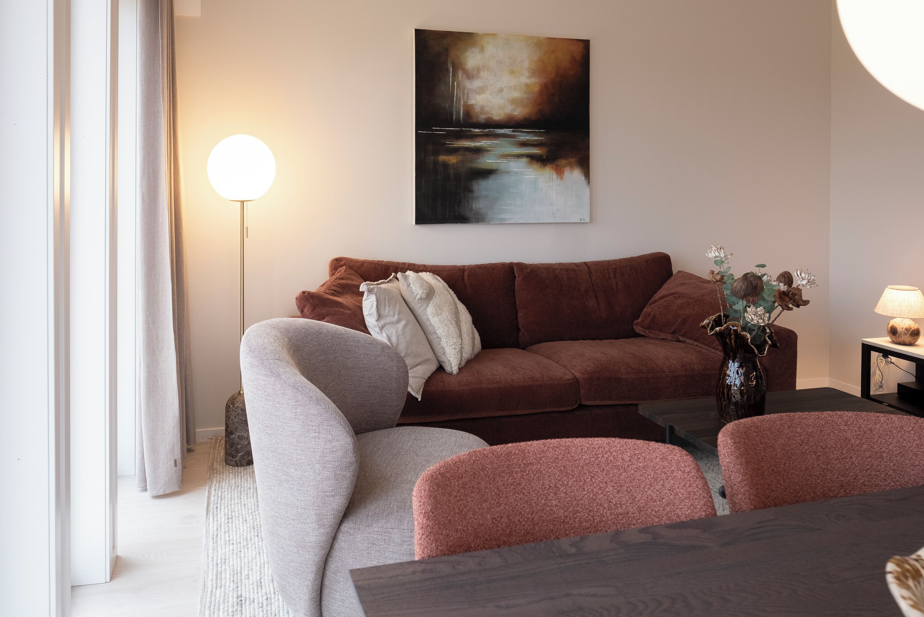Ein modernes Wohnzimmer mit einem braunen Sofa, einem grauen Sessel und einem Couchtisch aus Holz.