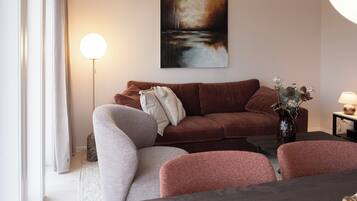 Ein modernes Wohnzimmer mit einem braunen Sofa, einem grauen Sessel und einem Couchtisch aus Holz.