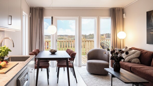 A modern kitchen with a dining area, a sofa, and a view of the outdoors. - Skerike Golfhus (Vasteras)