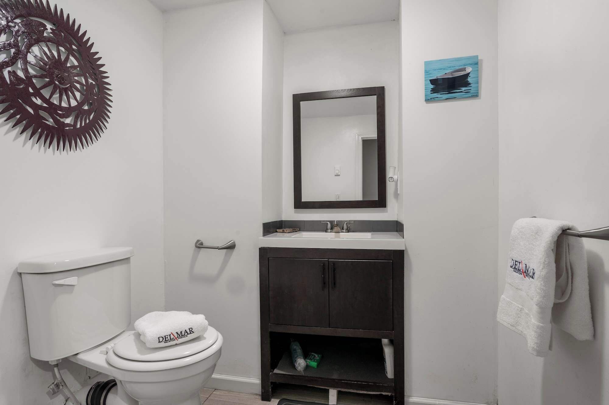 Un baño con inodoro, lavabo, espejo y toallero.