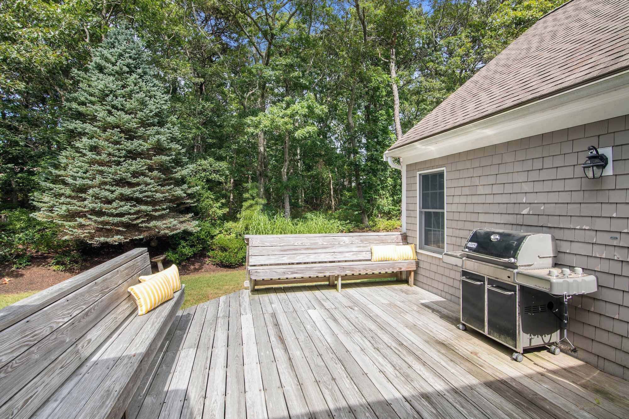 A wooden deck with a barbecue grill and a small shed.
