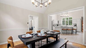 Comedor con una mesa de madera oscura dispuesta para cuatro personas, rodeada de sillas de cuero.