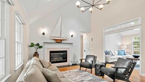 Un salón amplio con chimenea, un ventanal grande y una lámpara de techo moderna.