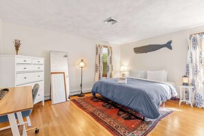 Une chambre à coucher comprenant un lit, un bureau, une commode, une lampe et une grande fresque murale représentant des poissons.