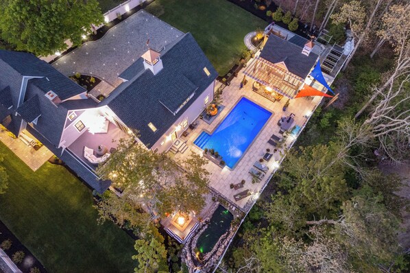 Une grande maison avec une piscine, un espace extérieur aménagé pour s’asseoir et une terrasse couverte.