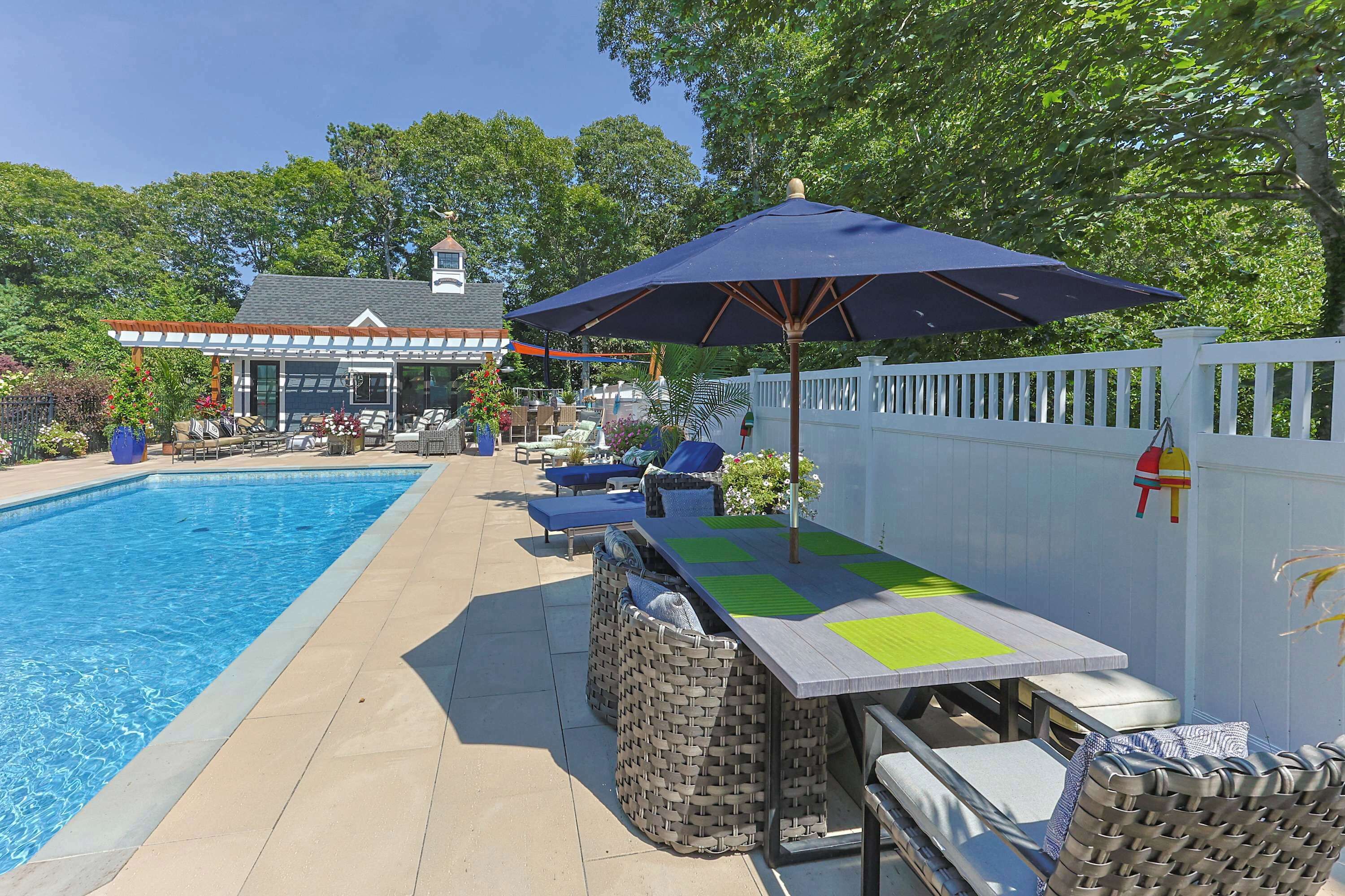 A swimming pool with lounge chairs and a table with an umbrella.