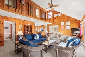 A spacious living area with a high ceiling, wooden walls, and a large television. - Steps to Neighborhood Beach, Dog Friendly! (Eastham)