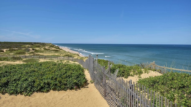 A beach with a wooden fence, sandy path, and ocean view. - Game Room, Walk to Two Landings! (Wellfleet)