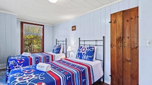 A bedroom with two beds, each with a nautical-themed bedspread and matching pillows. There is a wooden wardrobe and a window with blinds. - Game Room, Walk to Two Landings! (Wellfleet)