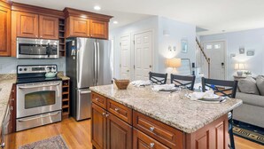 Una cocina moderna con armarios de madera, electrodomésticos de acero inoxidable y encimera de granito.