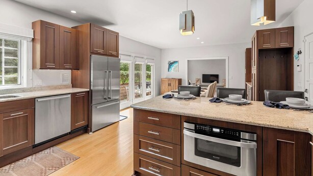 Een moderne keuken met houten kastjes, roestvrijstalen apparatuur en een groot eiland.