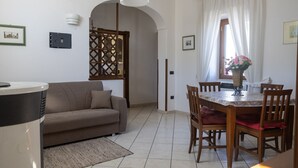A living room with a sofa, a dining table with chairs, a coffee table, and a decorative vase. - Al Primo Piano - Ischia (Forio)