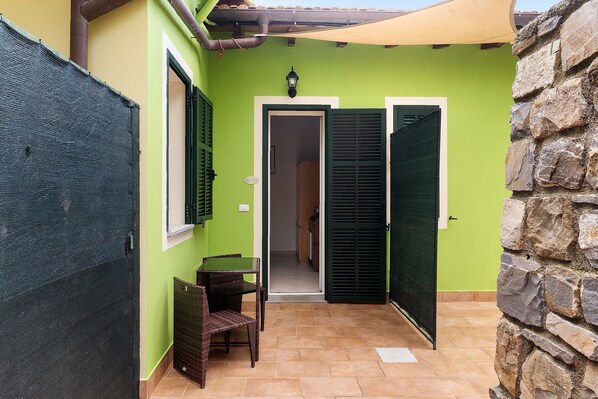 Un espace patio avec une table et des chaises, une porte et un mur en pierre.