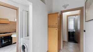 A kitchen with a stove, oven, and washing machine, a wooden cabinet, and a tiled floor. - Apartment with Private Garden and Wi-Fi in Santo Stefano al Mare (Santo Stefano al Mare)