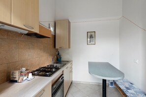 A compact kitchen with a gas stove, sink, and wooden cabinets.