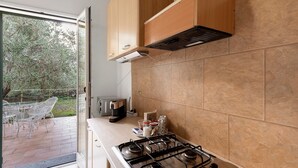 A kitchen with a gas stove, wooden cabinets, and a view of the outdoors. - Apartment with Private Garden and Wi-Fi in Santo Stefano al Mare (Santo Stefano al Mare)