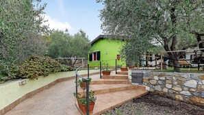 A green building with a stone wall and a wooden staircase leading to a door. - Apartment with Private Garden and Wi-Fi in Santo Stefano al Mare (Santo Stefano al Mare)