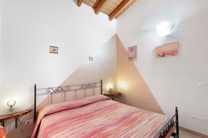 A bedroom with a bed, bedside tables, and wall-mounted lights.