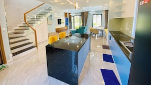 A modern hotel interior with a central island, a staircase, and a dining area. - Happy Stay Resort Novaworld Phan Thiet (Tien Thanh)