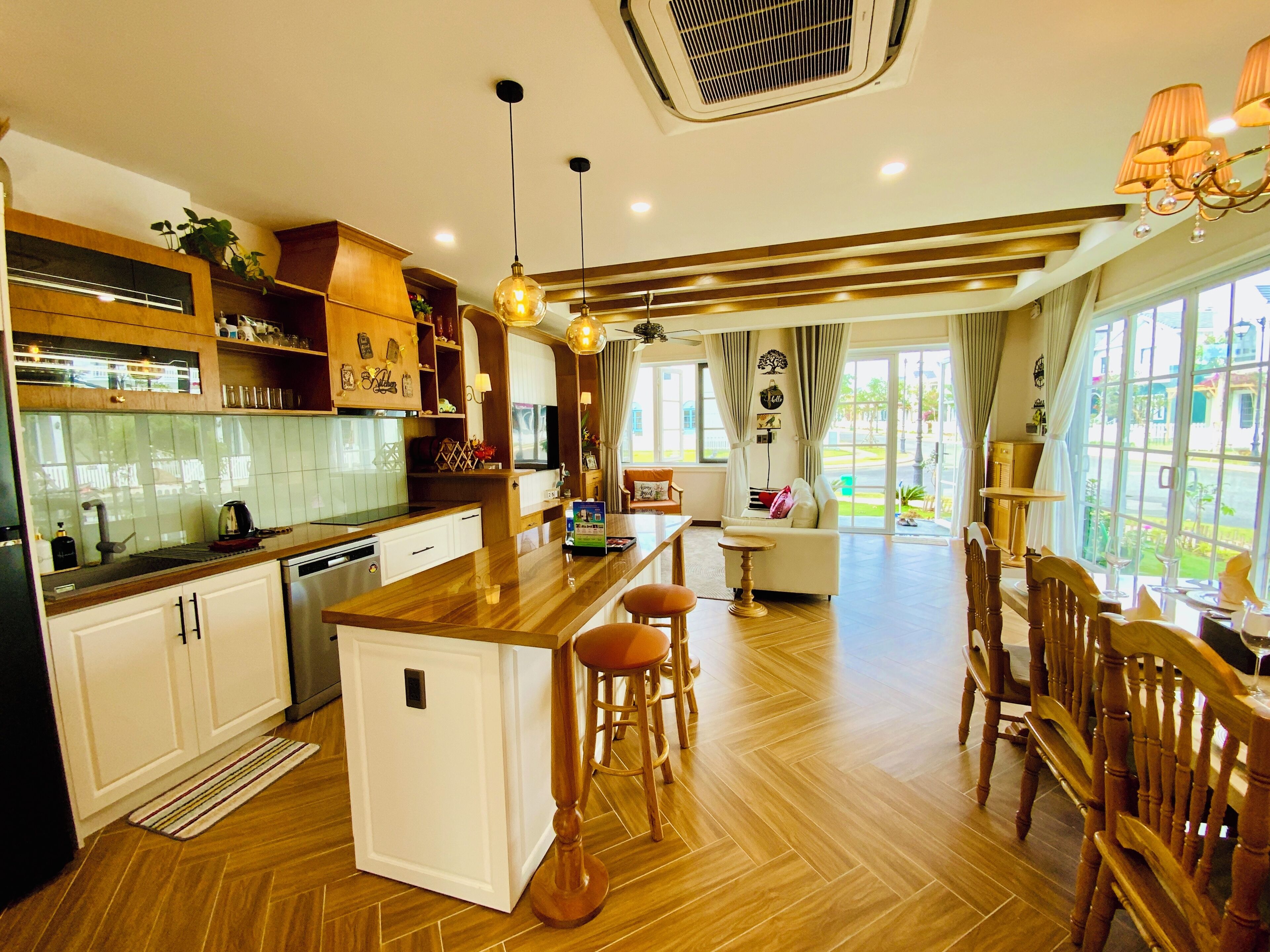 A modern kitchen with a central island, wooden cabinets, and a dining area with bar stools.