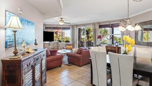 A spacious living area with a dining table, sofas, and a TV.