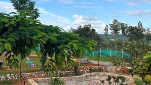 A park with exercise equipment, a stone wall, and lush greenery. - JUNGLE FARMS BY MAARK INN (Kanakapura)