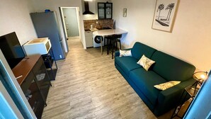 A compact living space with a kitchenette, a dining area, and a green sofa. - Bright studio a few steps from the beach (Saint-Mandrier-sur-Mer)