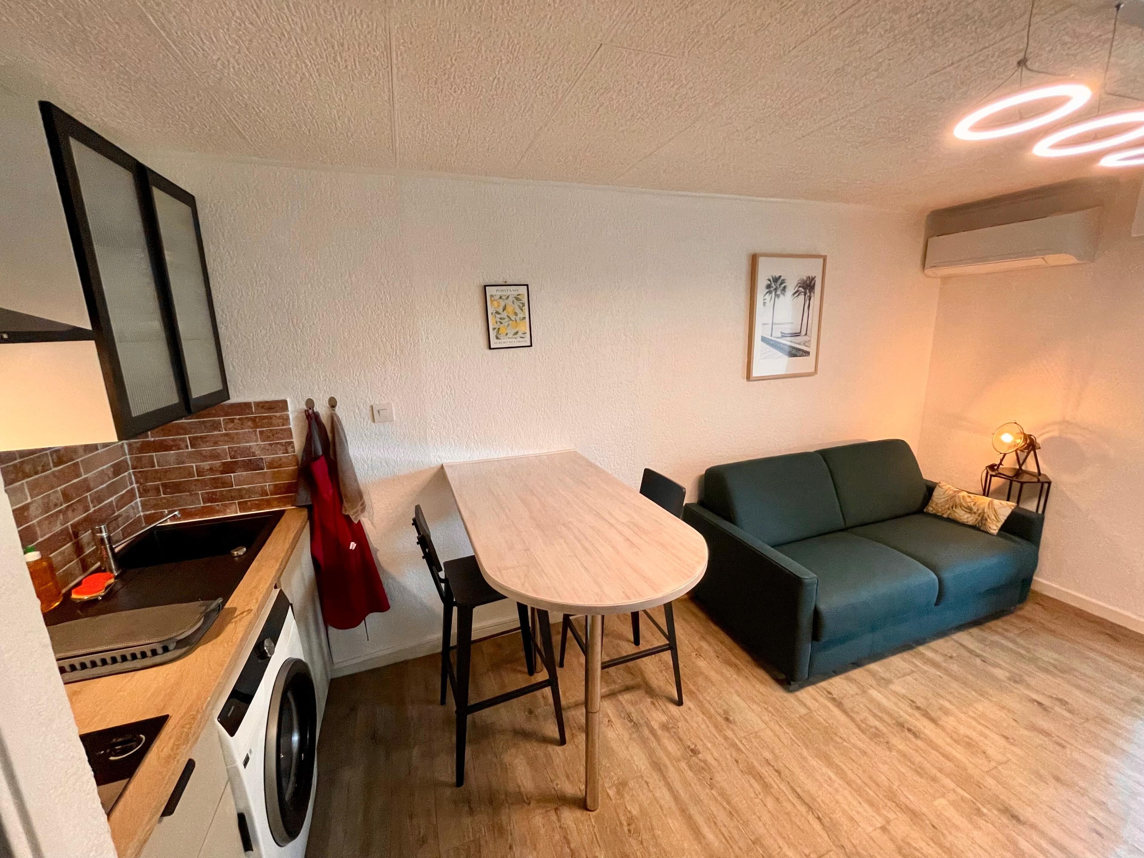 Un espace de vie compact comprenant une cuisine, un coin repas et un canapé.