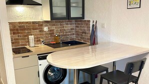 A compact kitchen with a washing machine, a sink, and a stove. - Bright studio a few steps from the beach (Saint-Mandrier-sur-Mer)