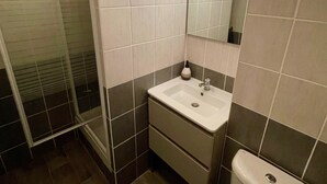 A bathroom with a shower, a sink, a mirror, and a toilet. - Bright studio a few steps from the beach (Saint-Mandrier-sur-Mer)