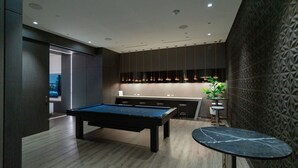 A modern pool table in a room with a wooden floor, a bar area with stools, and a patterned wall. - Fully Furnished One Bedroom apartment in the heart of North York (North York)