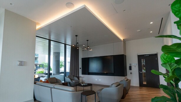 Uma sala de estar moderna com uma grande TV de tela plana, um sofá seccional e uma mesa de centro.