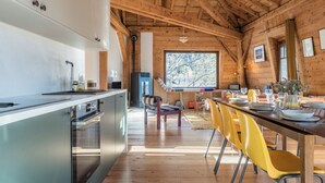 A modern kitchen with stainless steel appliances, wooden beams, and a dining area with yellow chairs. - Spacious flat in the centre of Chamonix (Chamonix-Mont-Blanc)