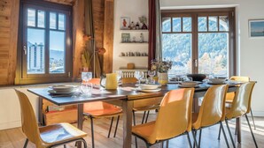 A dining area with a wooden table set for four, surrounded by orange chairs. - Spacious flat in the centre of Chamonix (Chamonix-Mont-Blanc)